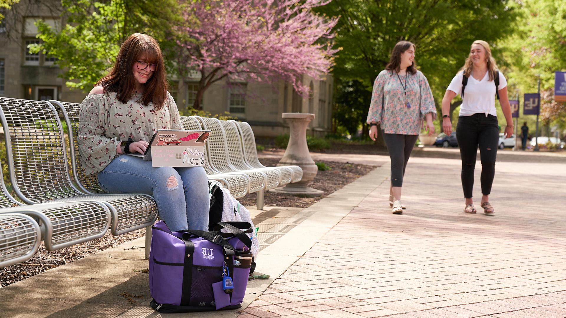 Student sitting on bench with laptop